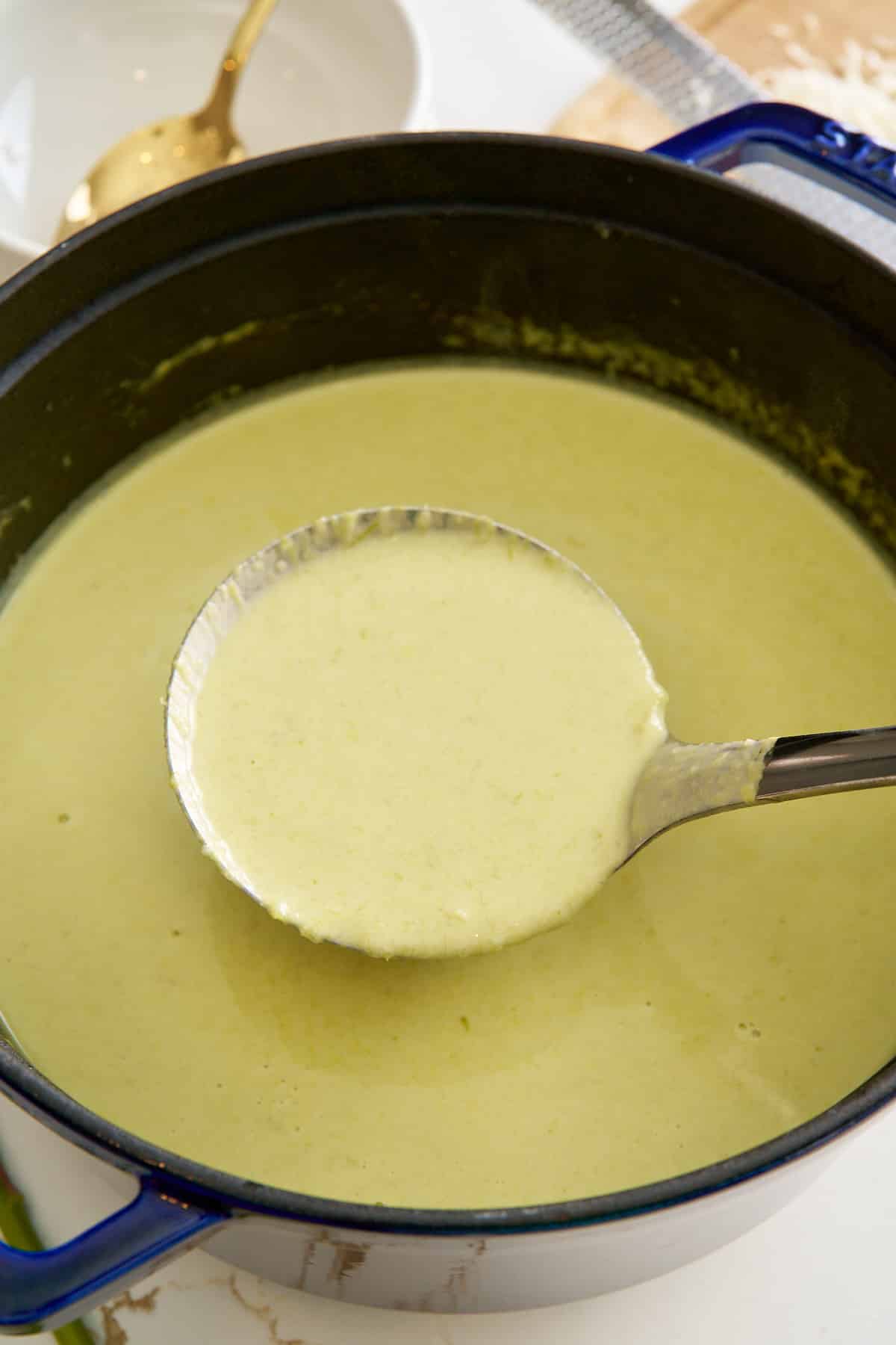 finished asparagus soup in pot being picked up with ladle