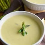 cream of asparagus soup in bowl with asparagus garnish on top