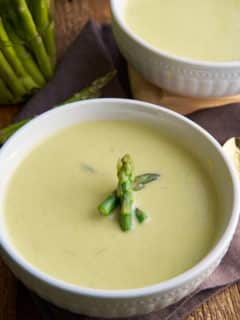 cream of asparagus soup in bowl with asparagus garnish on top