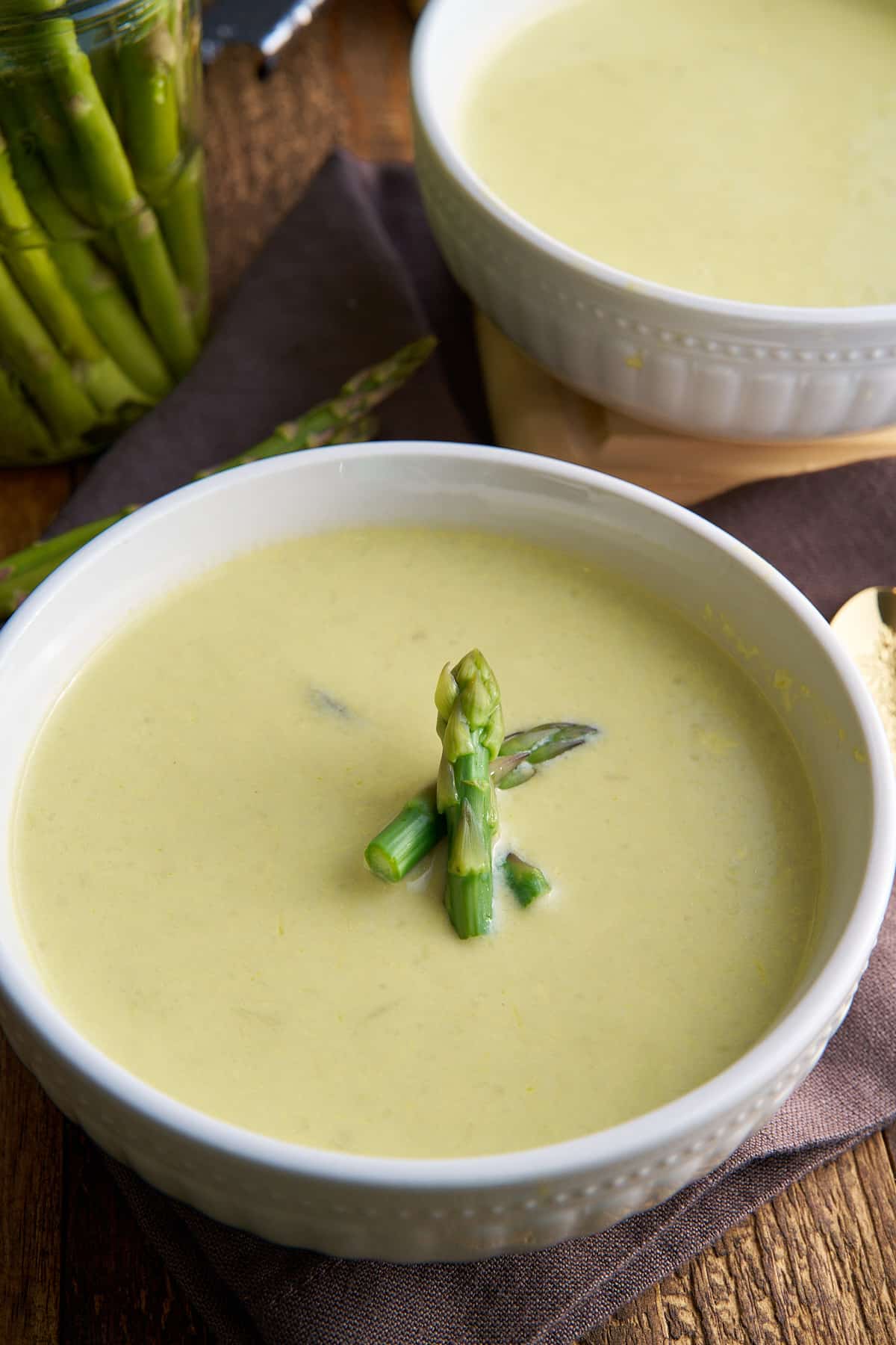 cream of asparagus soup in bowl with asparagus garnish on top
