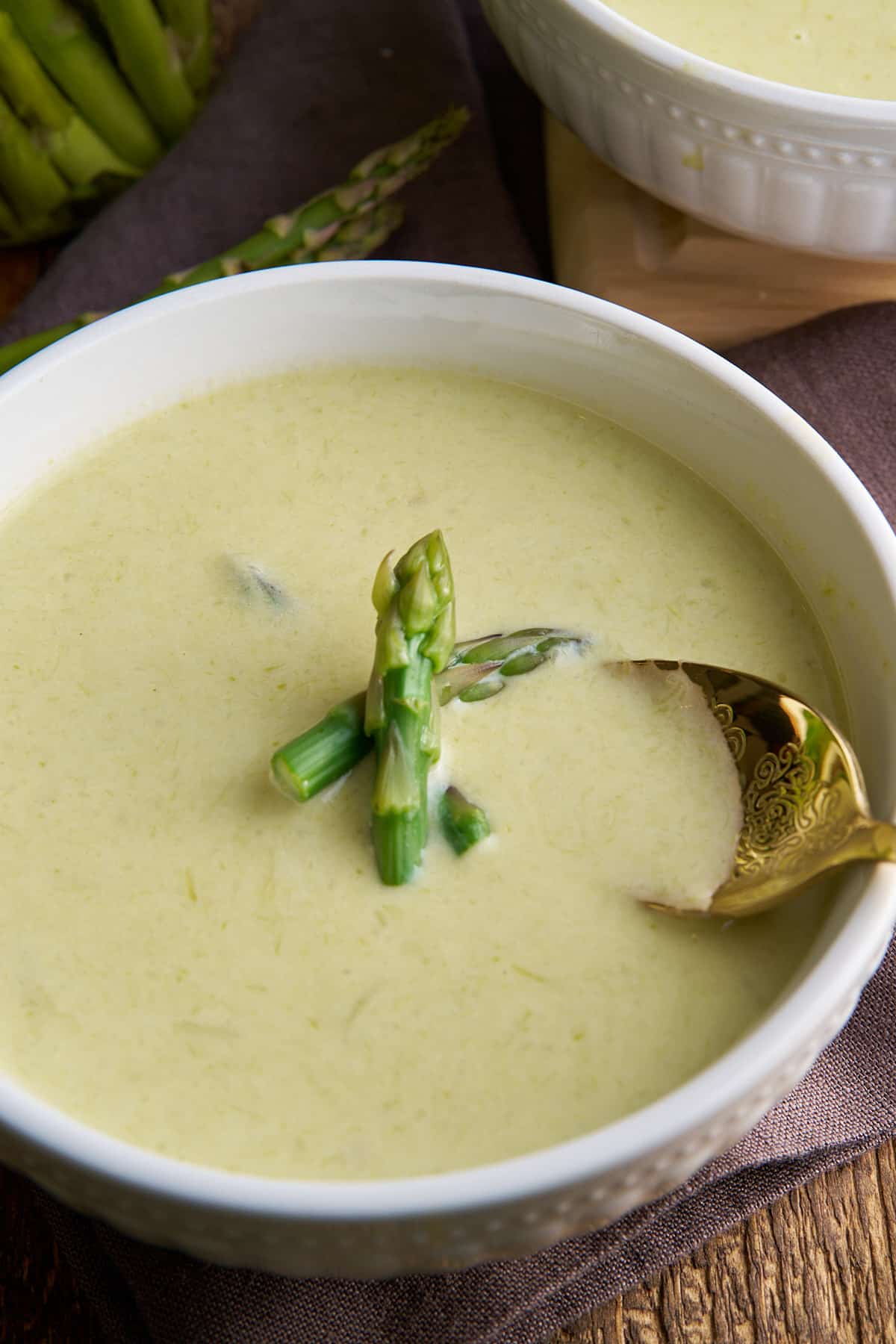 spoon dipping in asparagus soup in bowl