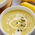 yellow squash soup in bowl with yellow squash in back