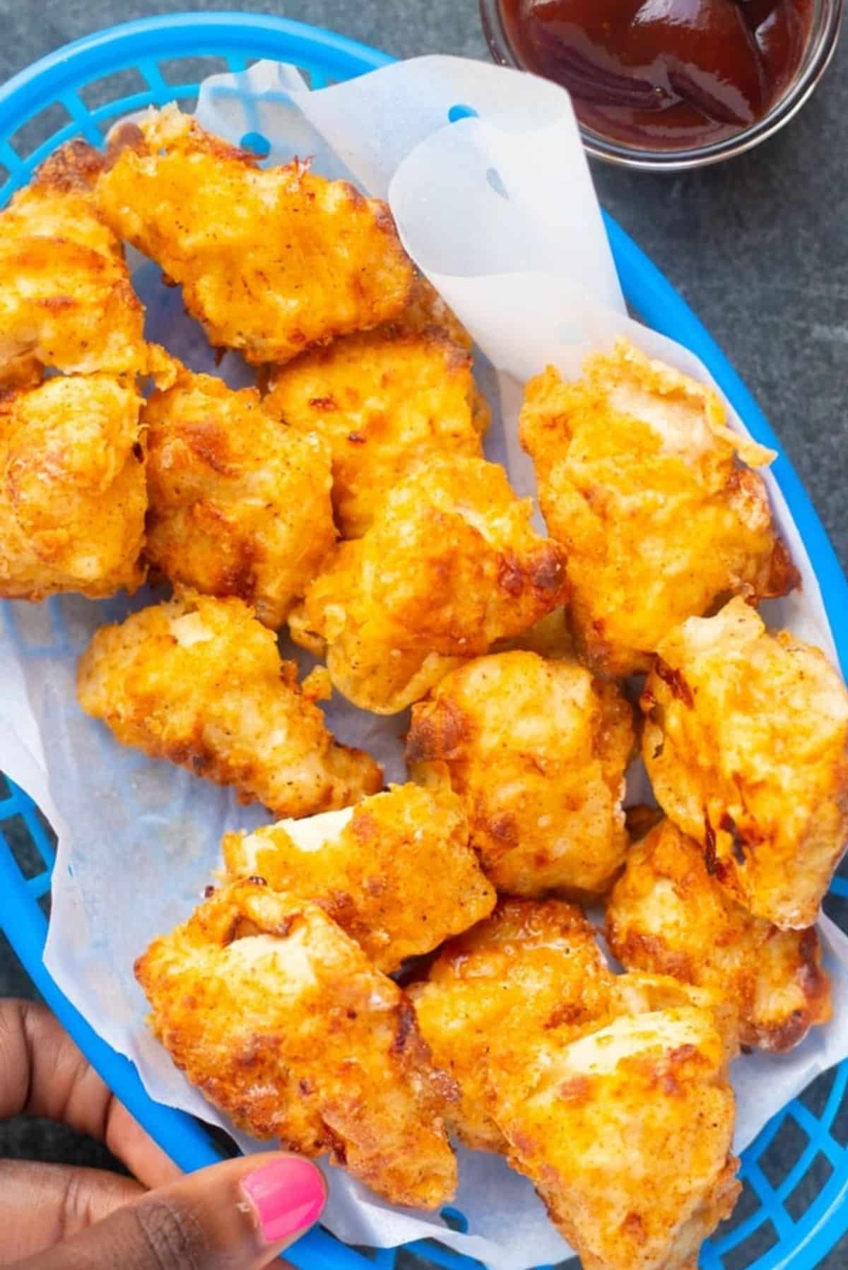 air fryer chicken nuggets in blue basket with parchment paper liner