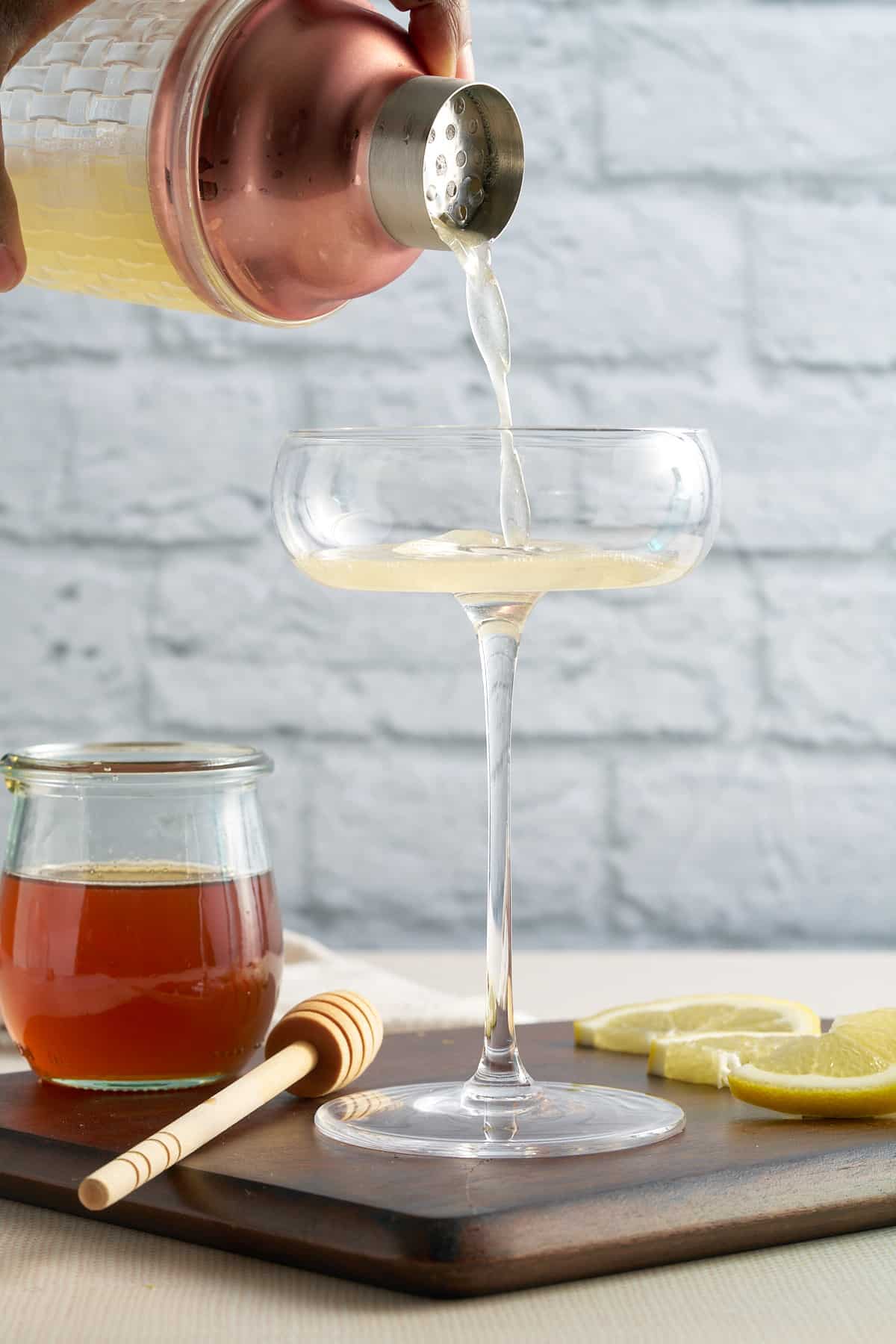 cocktail being poured into a coupe glass