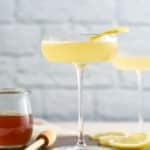 the cocktail in a glass with honey syrup next to it