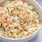 tuna pasta salad in white bowl with tuna can in corner