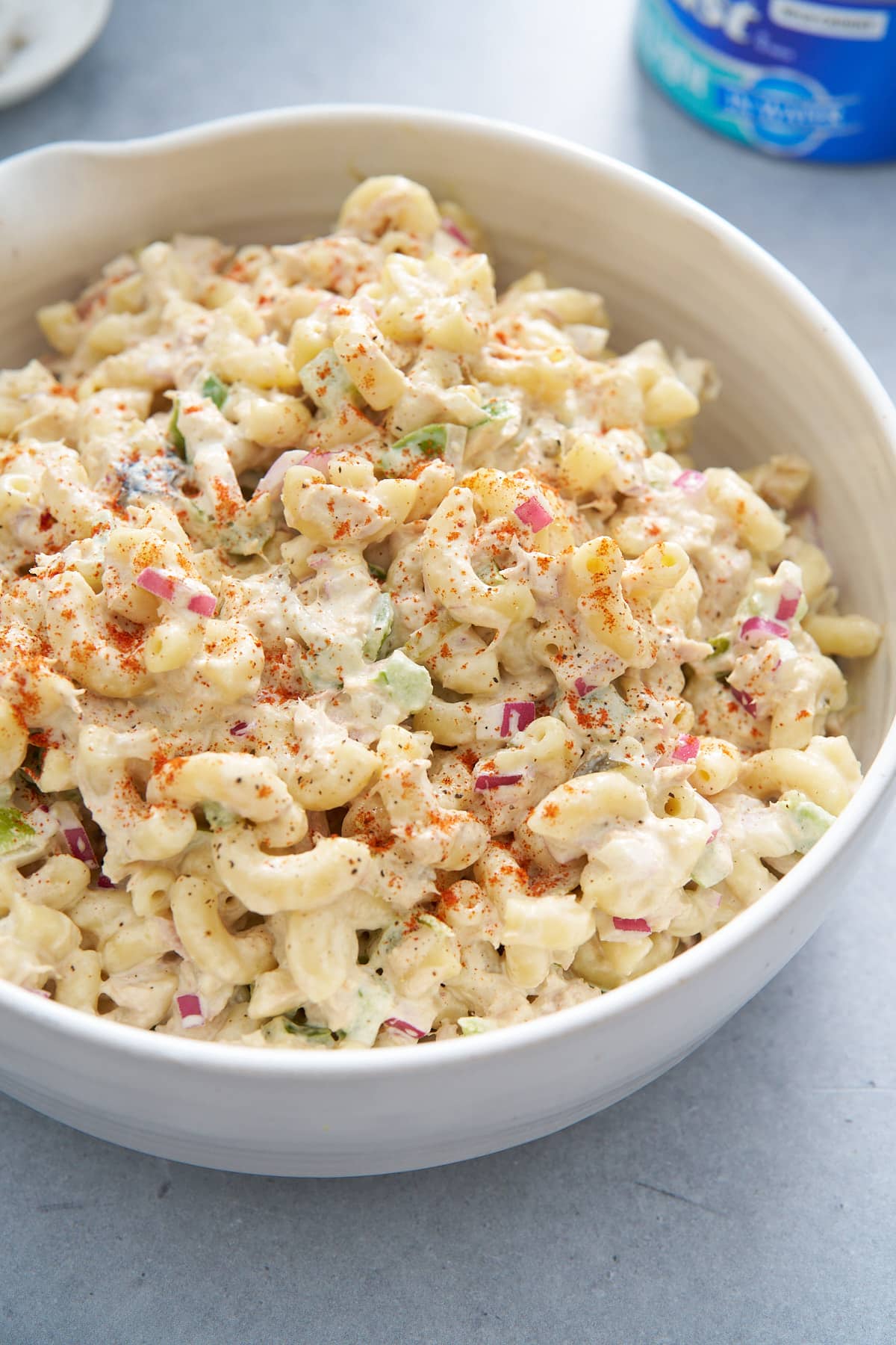 tuna pasta salad in white bowl with tuna can in corner