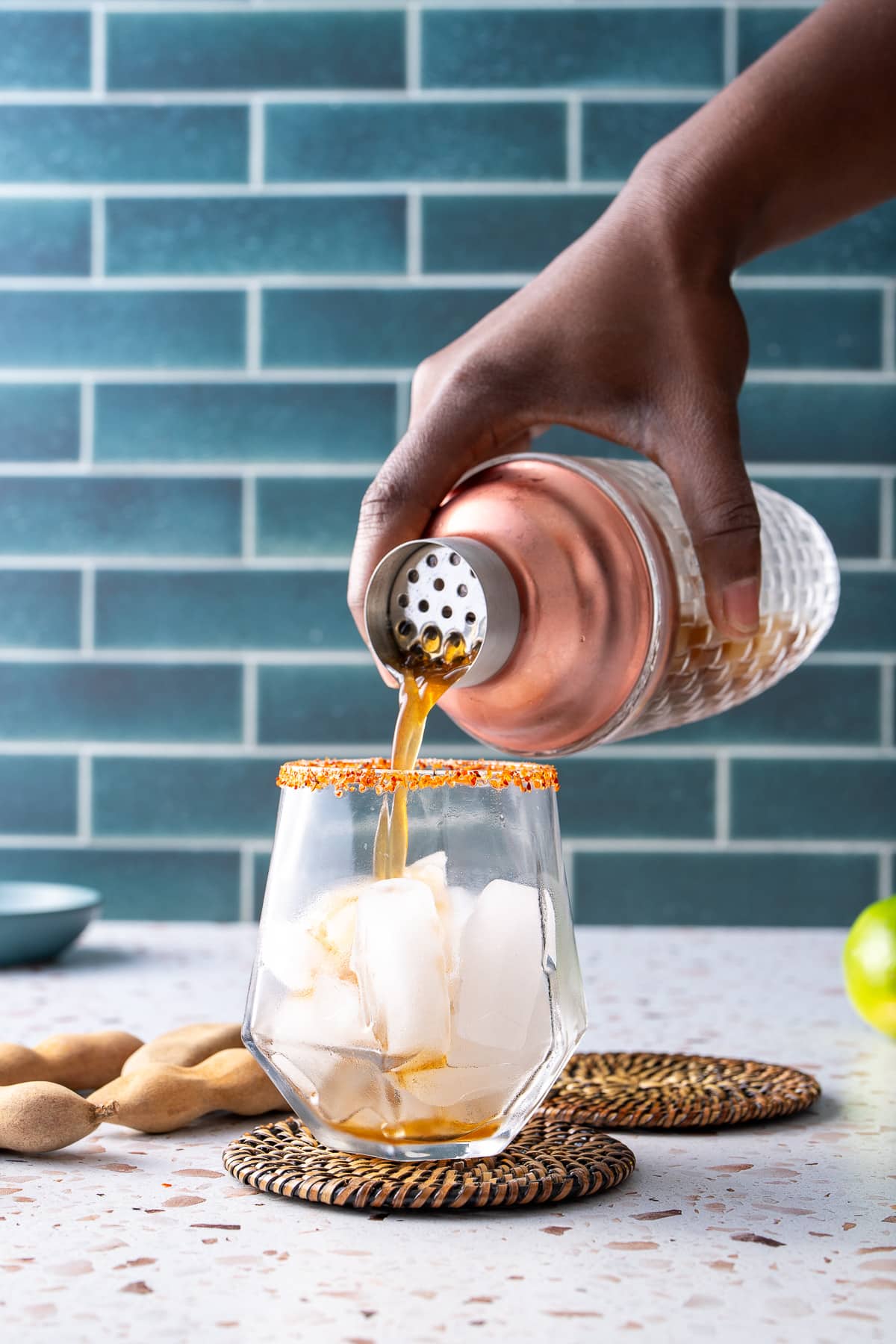 cocktail being poured into glass with ice from shaker