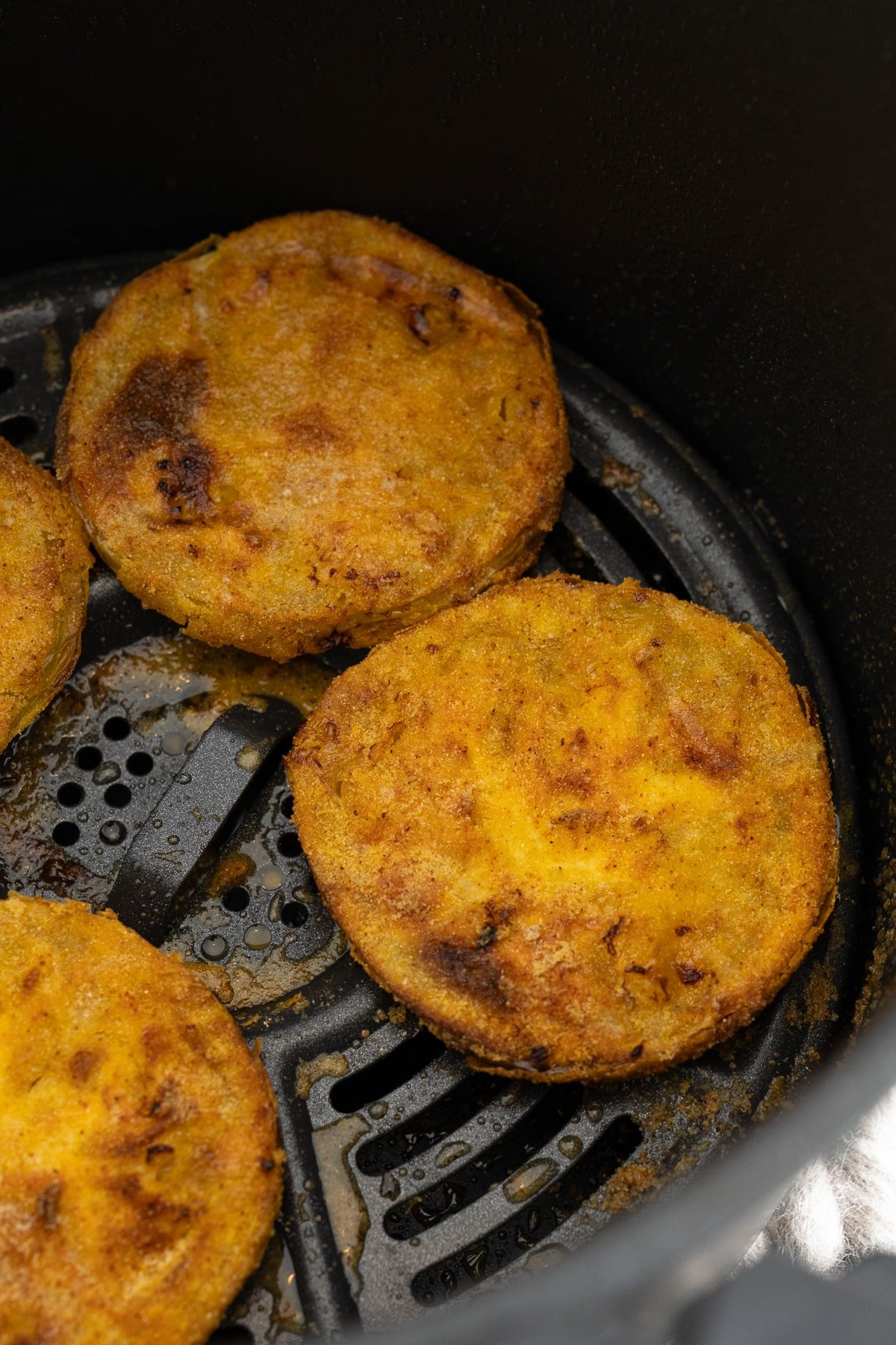 cooked fried green tomatoes in air fryer basket