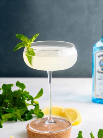 southside cocktail in glass with mint on side and gin bottle in corner