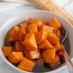 candied sweet potatoes in bowl with spoon sticking out