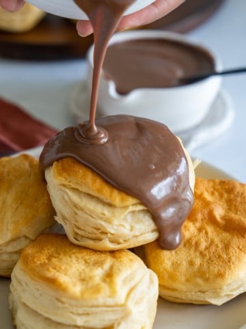 chocolate gravy being poured over biscuits