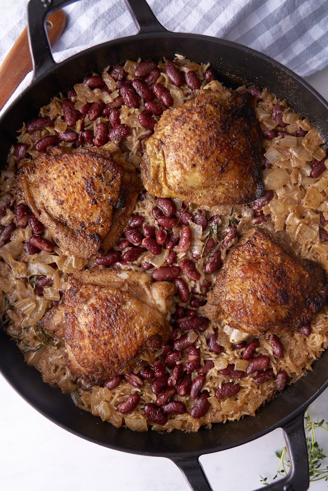 chicken cooked in skillet sitting on rice and peas