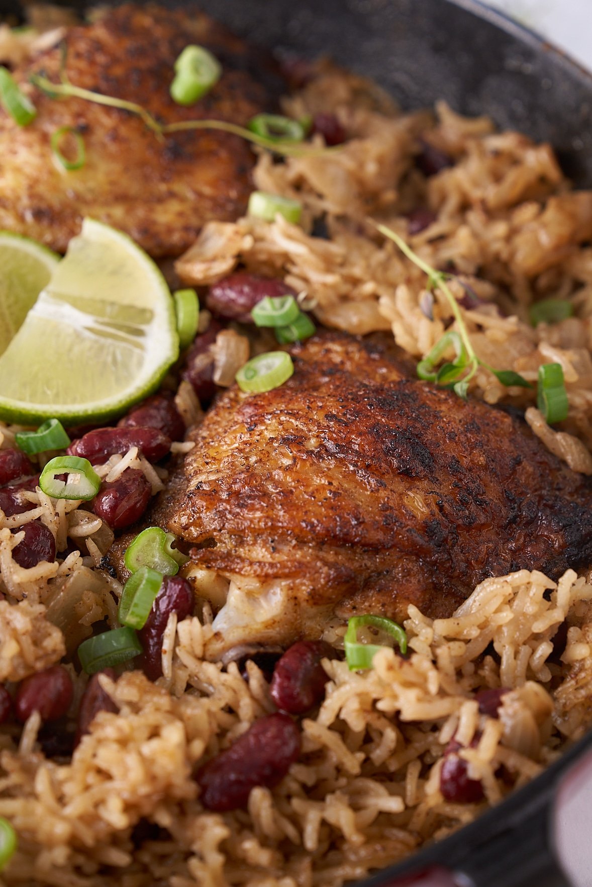 jerk chicken sitting on top of the rice and peas