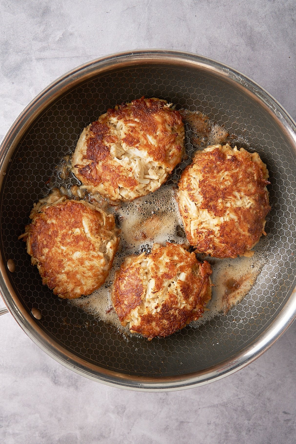 crab cakes being seared in a skillet