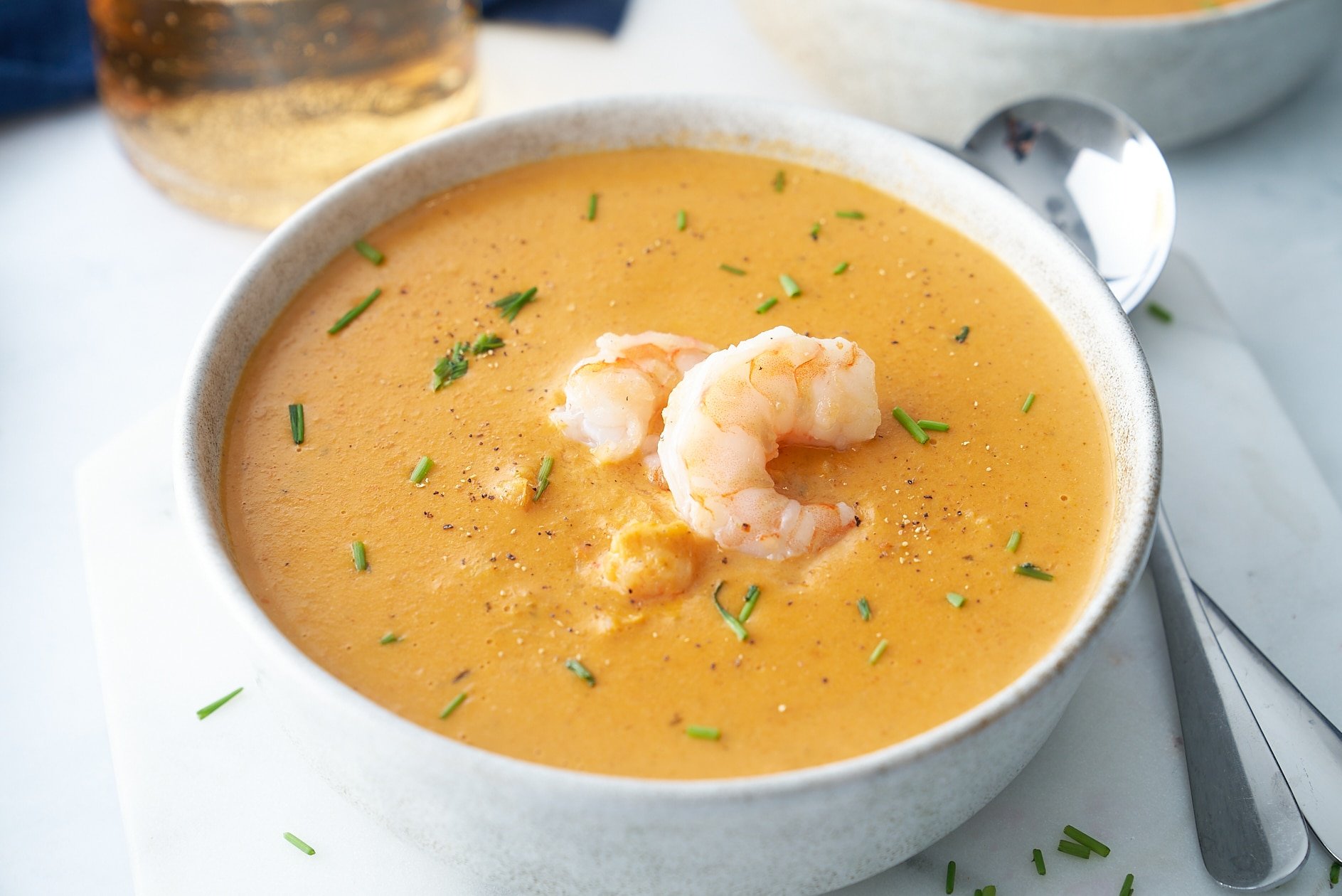 shrimp bisque in bowl with spoon on the side