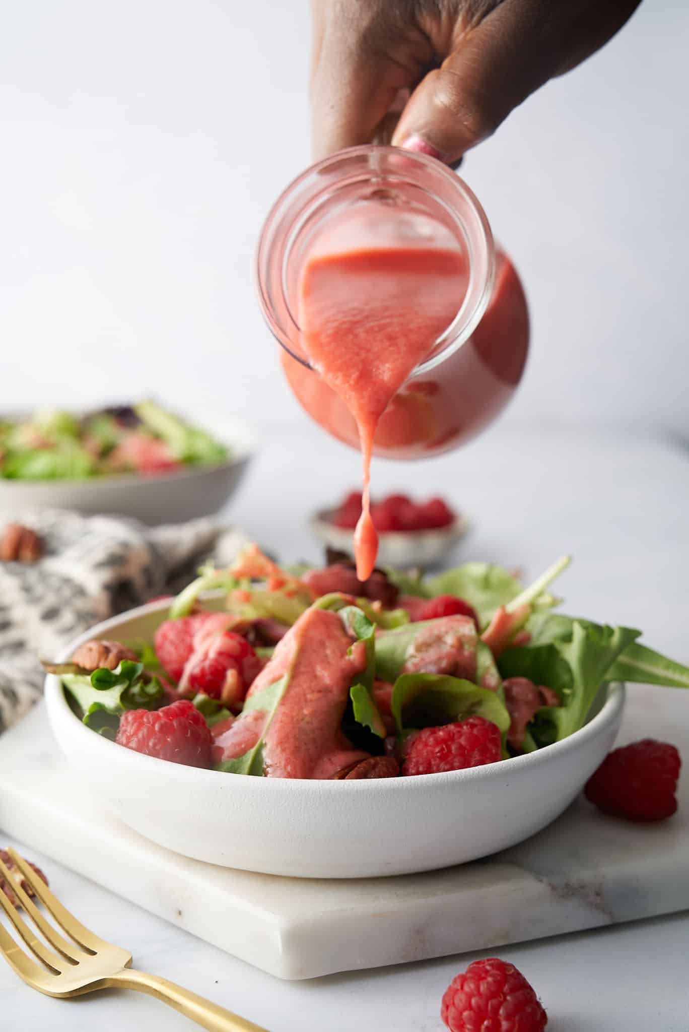raspberry vinaigrette being poured onto the salad