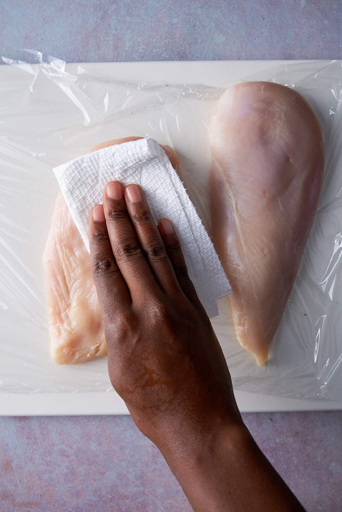 hand patting chicken breast dry