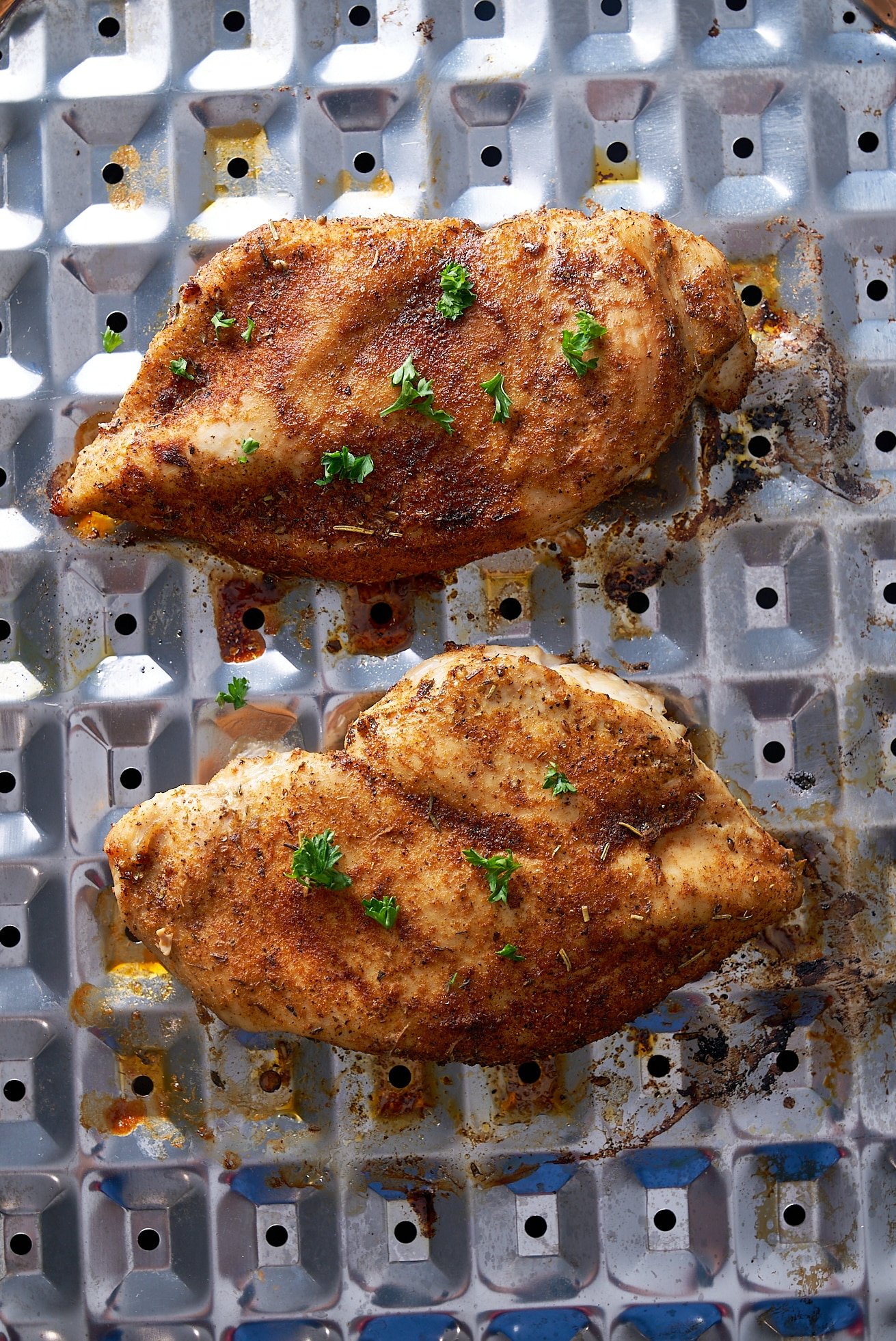 2 broiled chicken breast on broiler pan with parsley on top