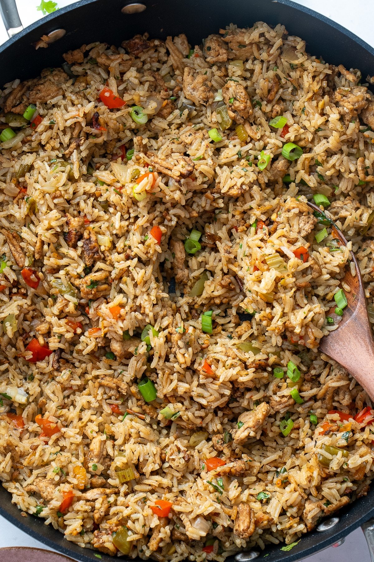 dirty rice in skillet with spoon picking it up