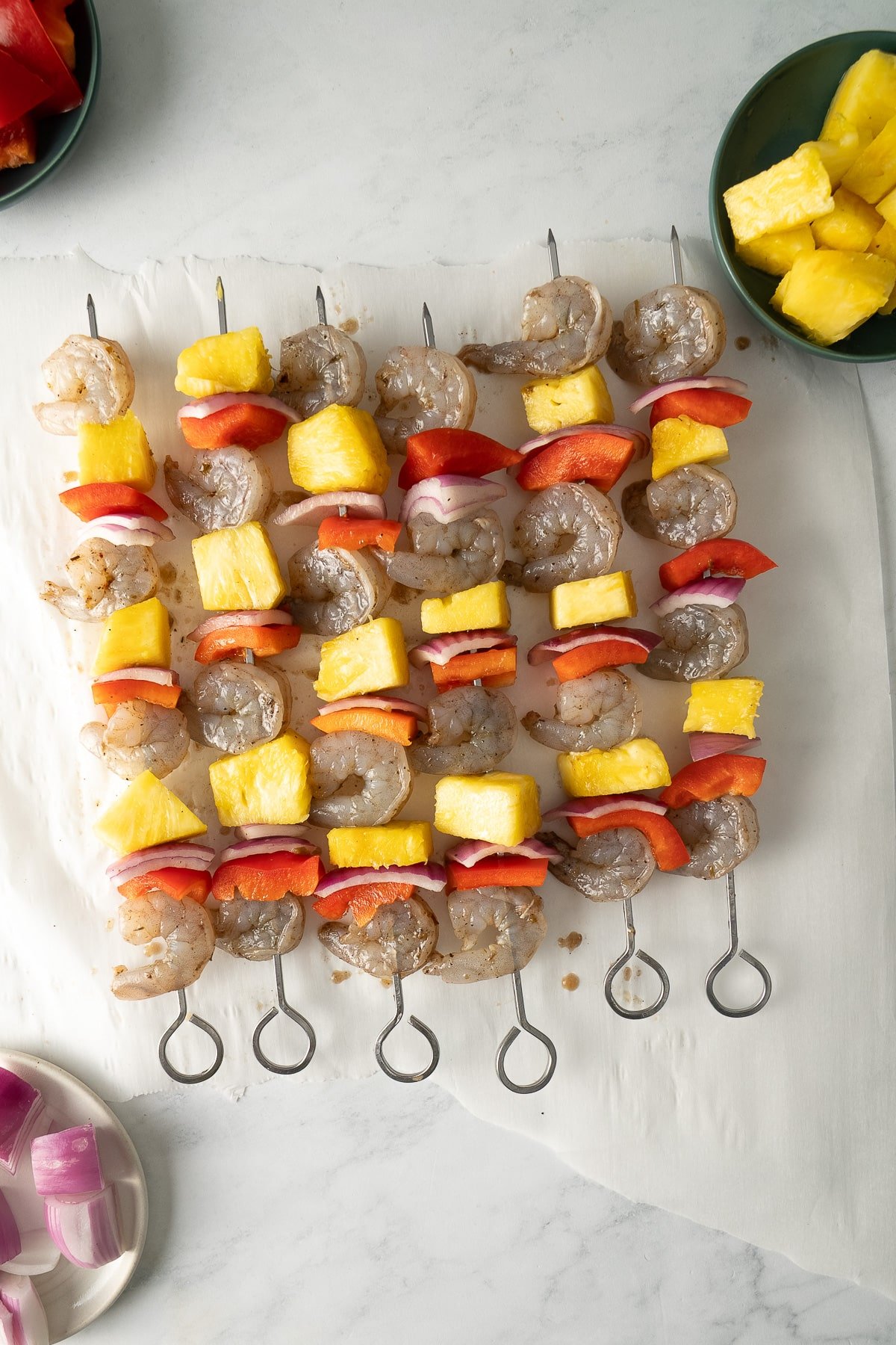 shrimp, pineapple, red bell pepper, and red onion on metal skewers
