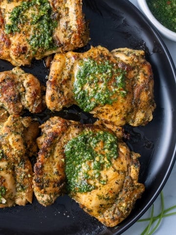 chimichurri chicken covered in the sauce on black plate