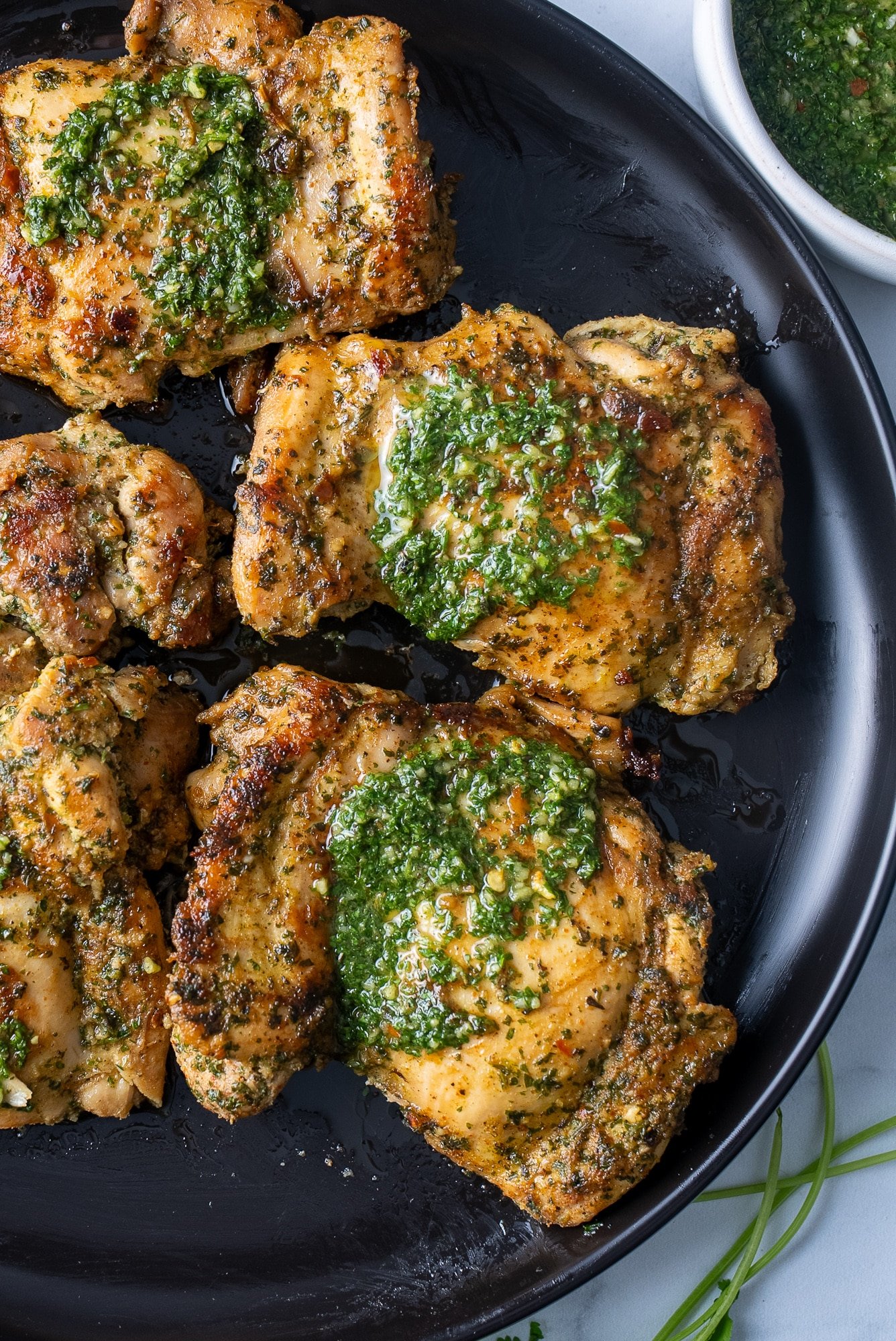 chimichurri chicken covered in the sauce on black plate