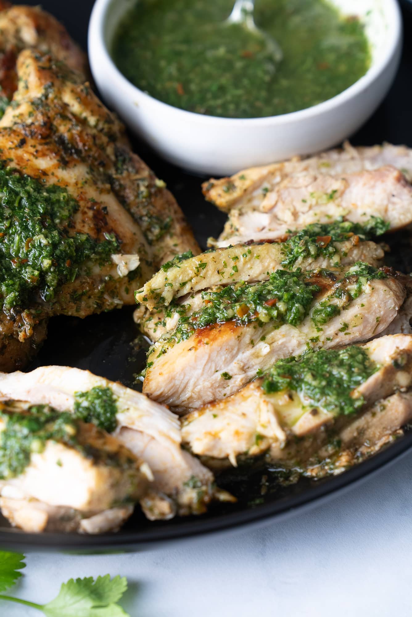 chicken sliced on plate covered in chimichurri sauce