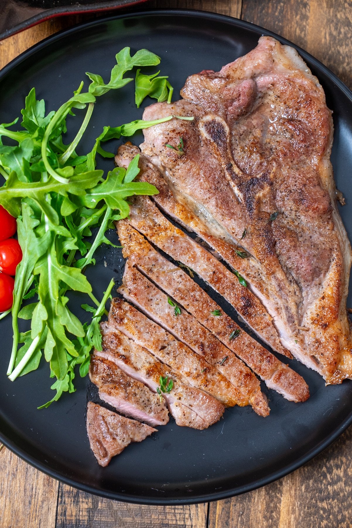 cooked pork steak on plate sliced next to salad