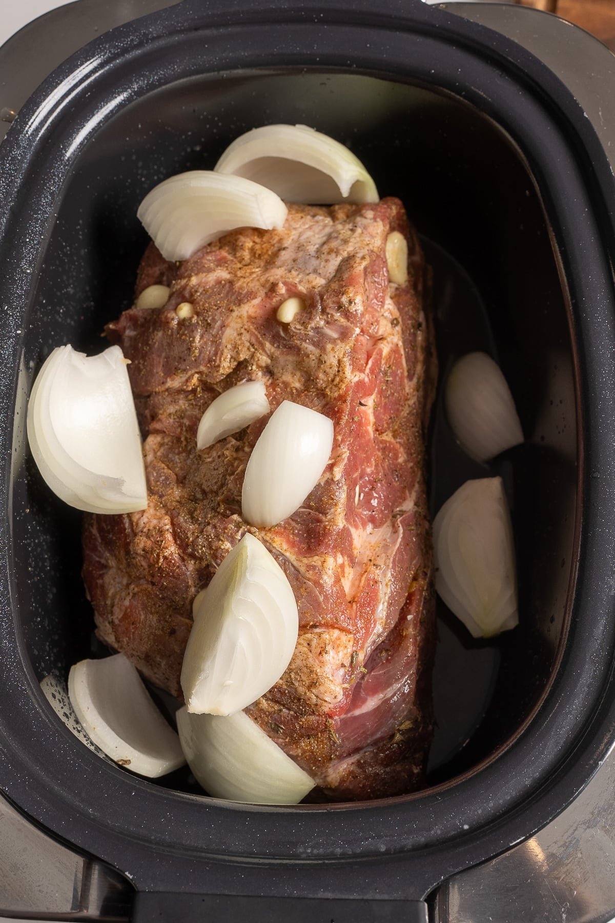 raw pork in slow cooker covered with onions and citrus juice