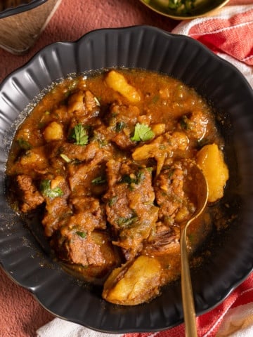 stovetop beef stew in black bowl with spoon in bowl
