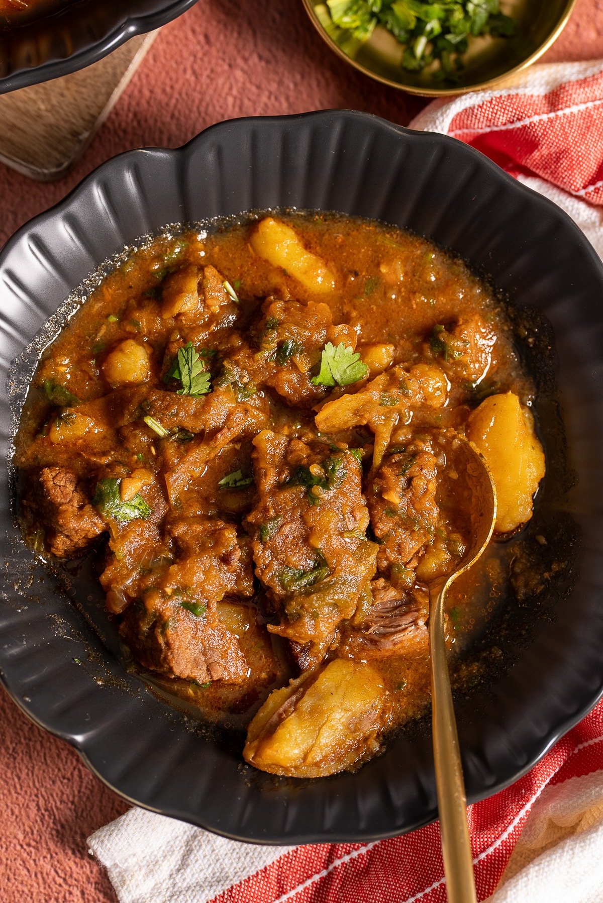 stovetop beef stew in black bowl with spoon in bowl