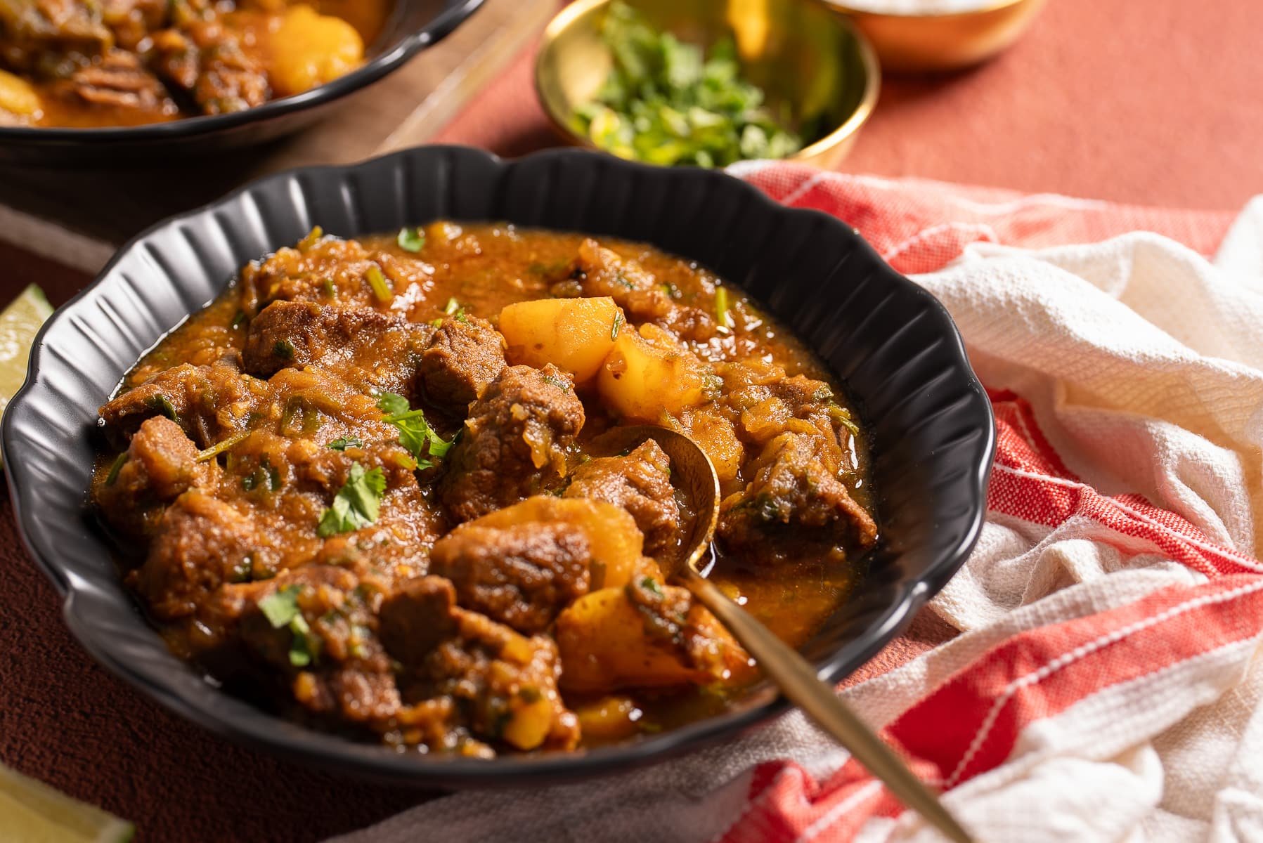 beef stew in black bowl next to napkin