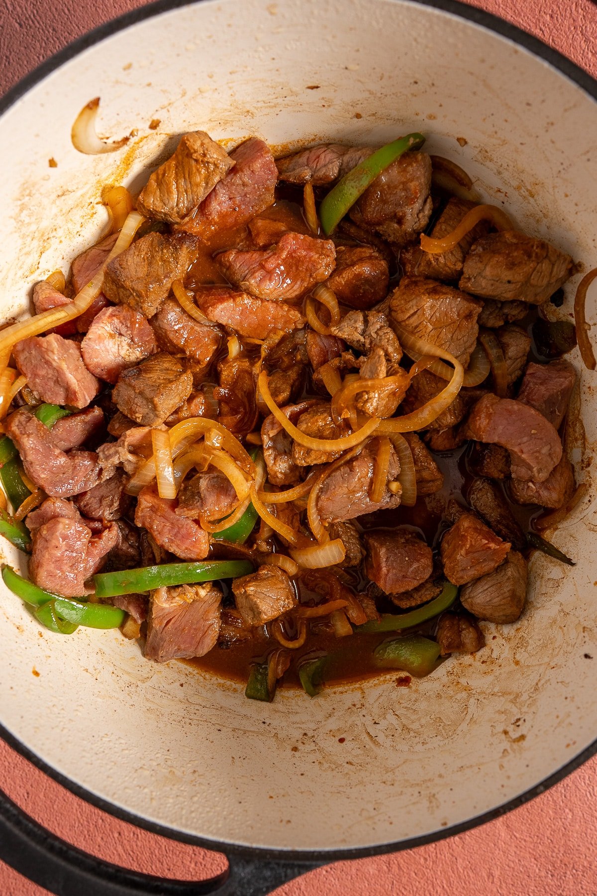 raw beef stew meat and peppers in pot