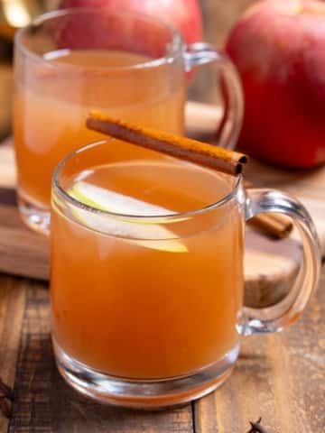 two glasses of homemade apple cider in mugs