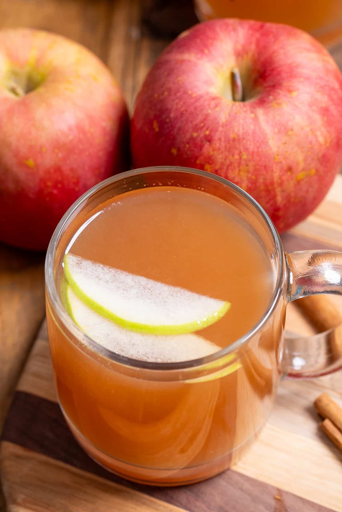 close up of homemade apple cider with apple slices on top