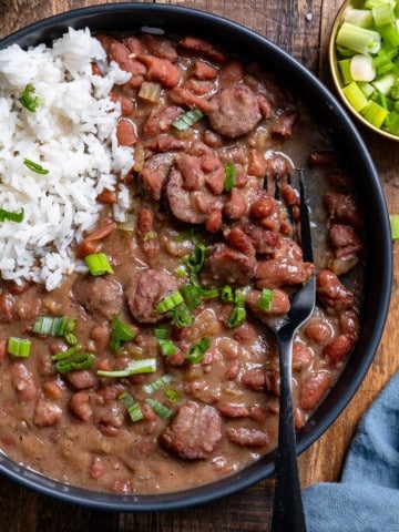 overhead of red beans and rice in black bowl with fork picking up beans