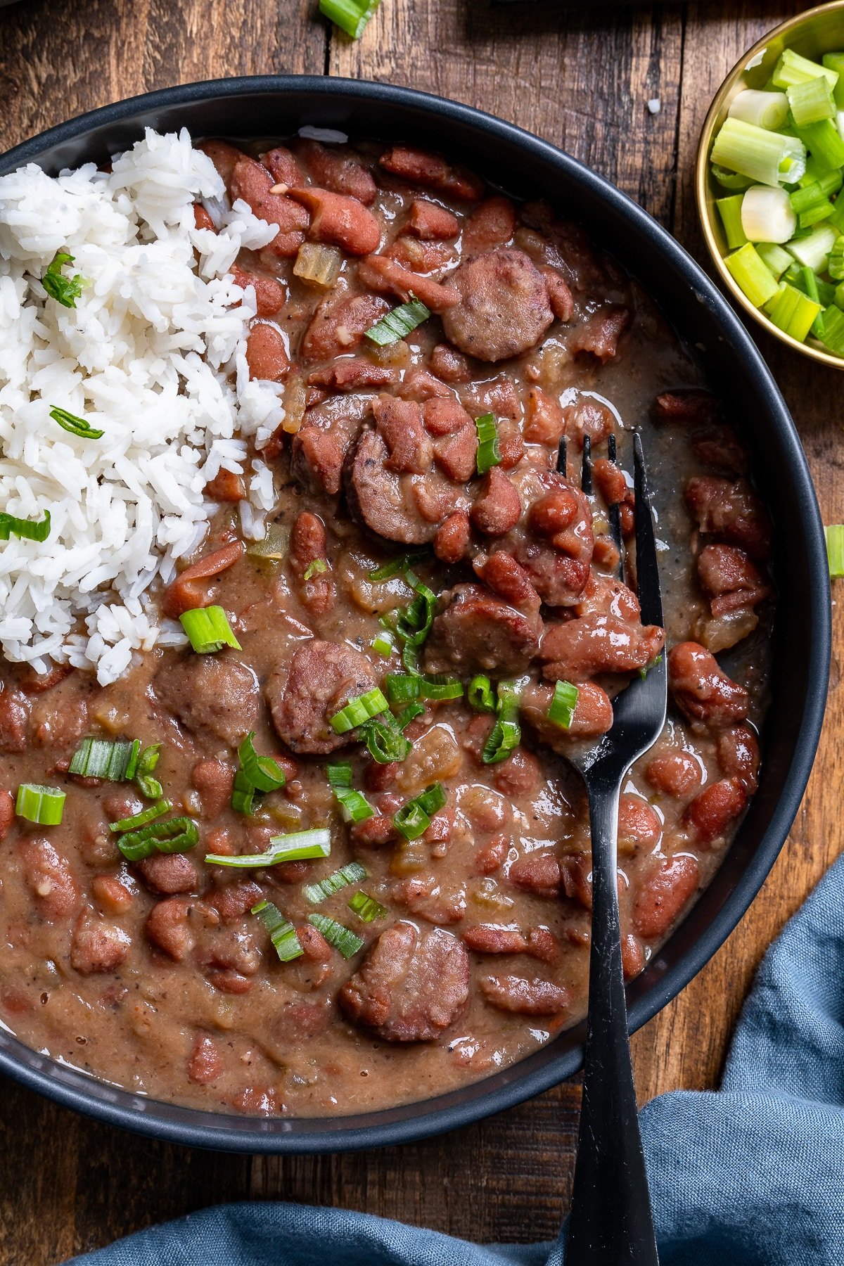 overhead of red beans and rice in black bowl with fork picking up beans