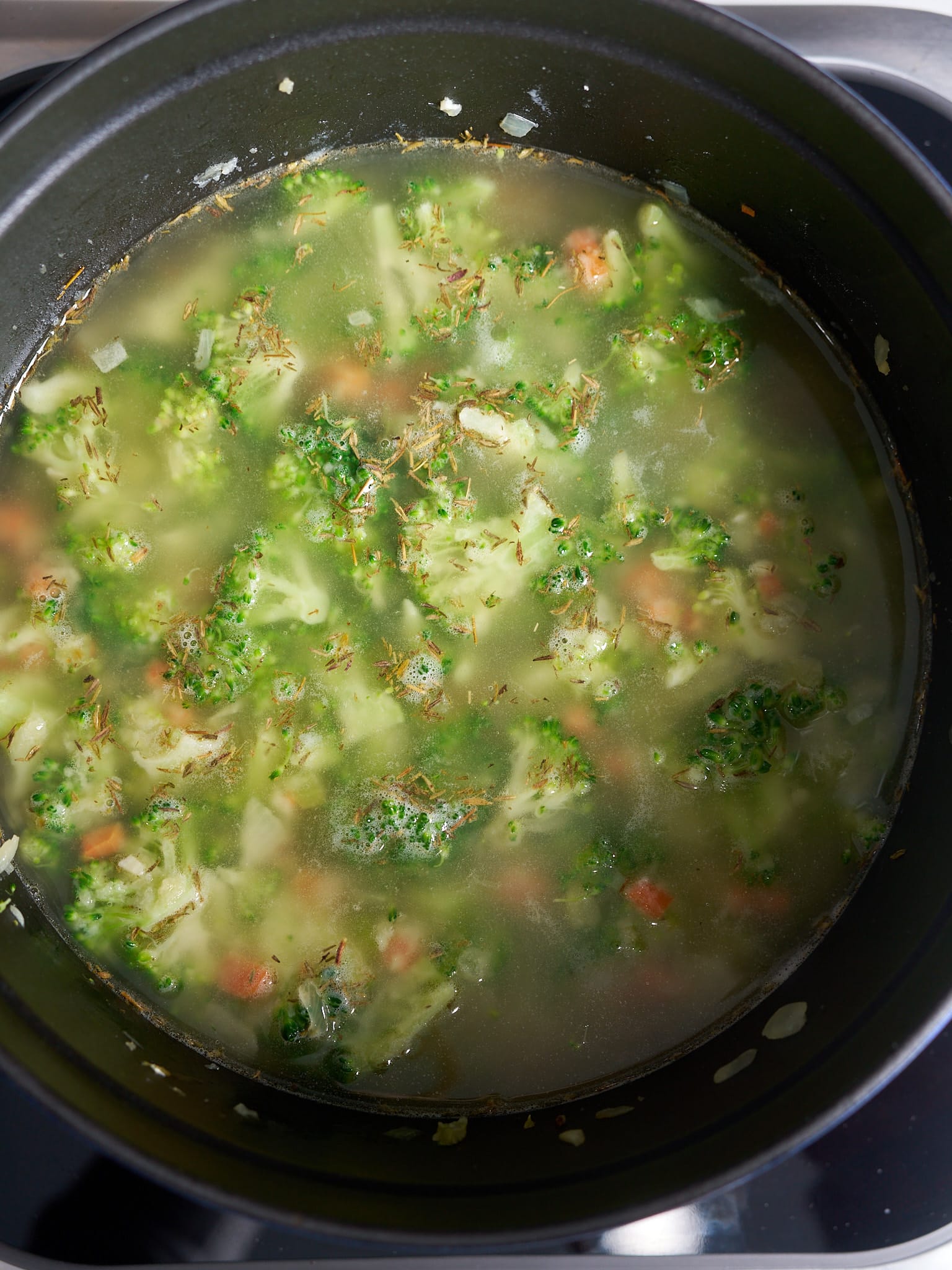 broccoli and vegetables covered in broth in pot