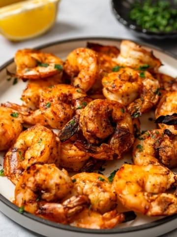 broiled shrimp on plate with lemon and pardley in background
