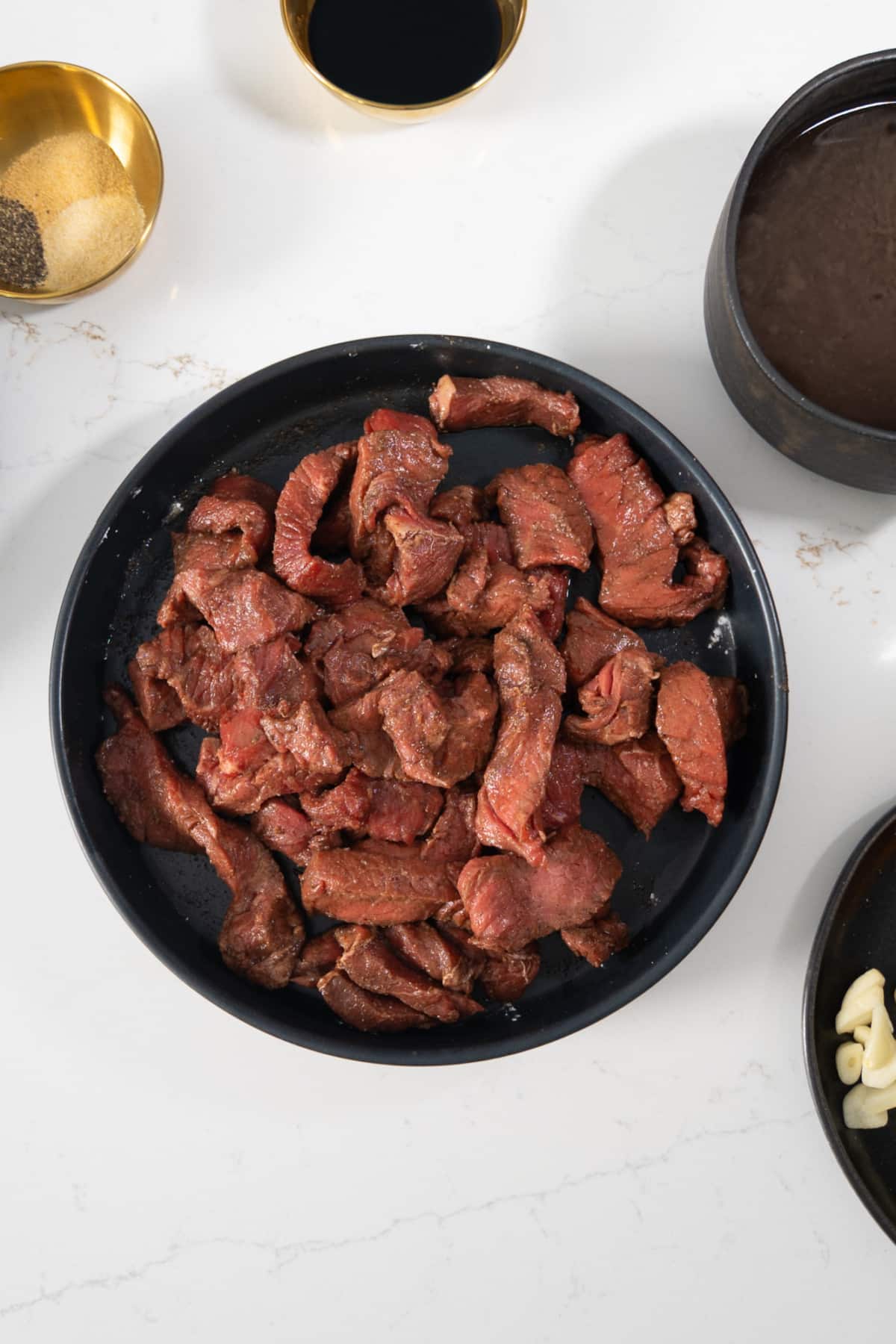 Steak being marinated in a bowl.