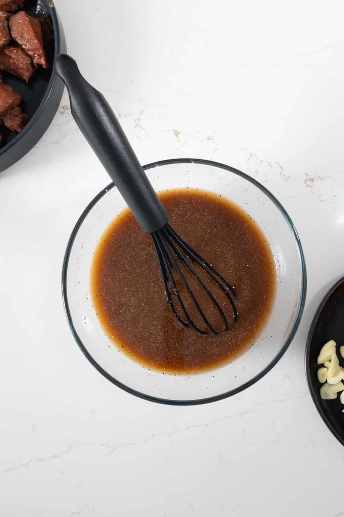 Sauce for pepper steak with whisk in bowl.