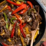 Jamaican pepper steak in a bowl with a spoon lifting up some of the pepper steak.