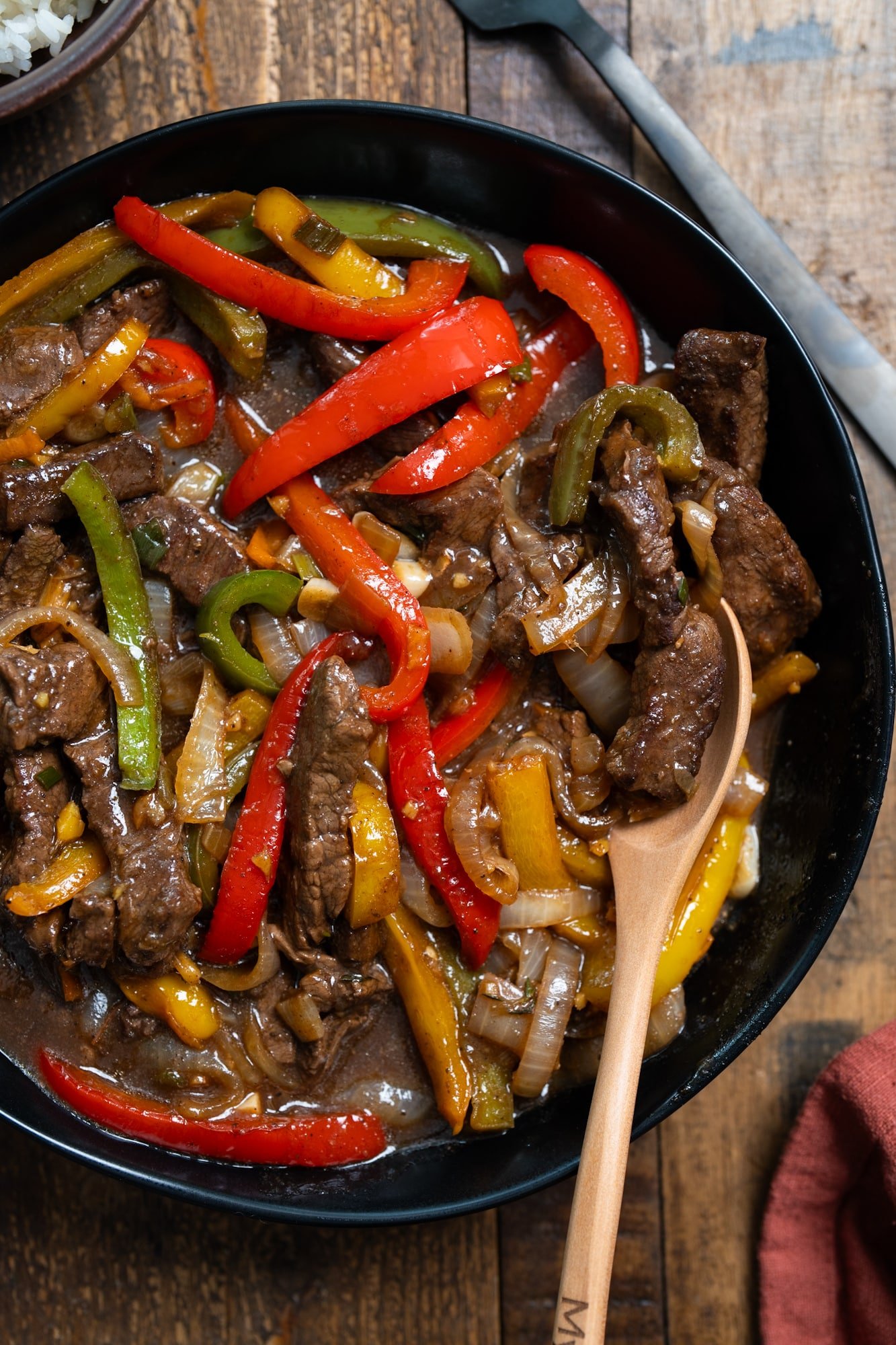 Jamaican pepper steak in a bowl with a spoon lifting up some of the pepper steak.