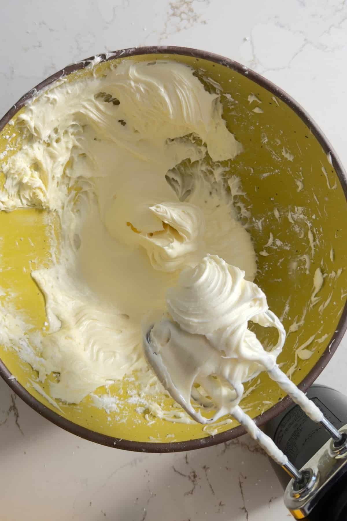Cream cheese frosting on mixer whisks