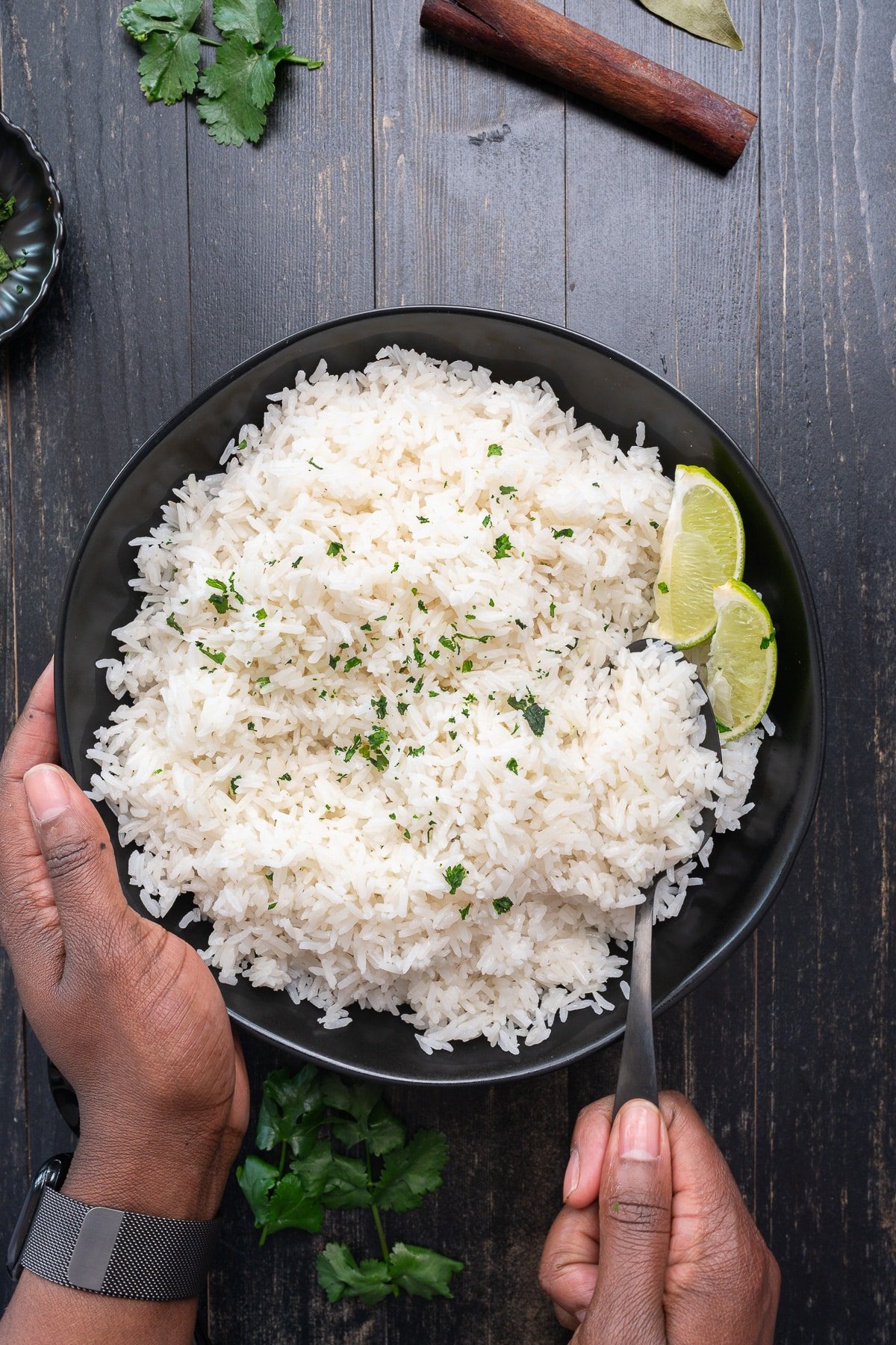 coconut rice fluffed with fork with hand holding the bowl