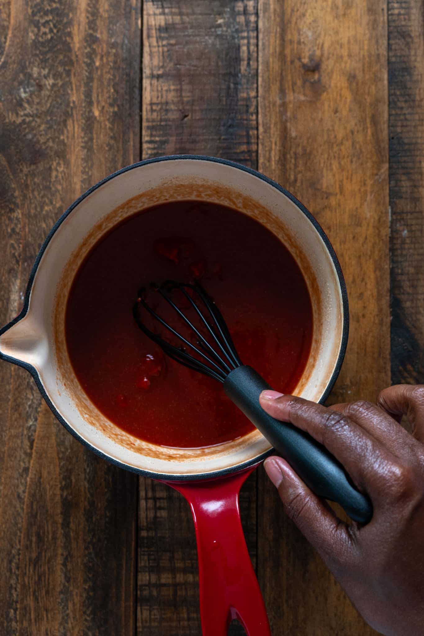 hand whisking ketchup ingredients in pot
