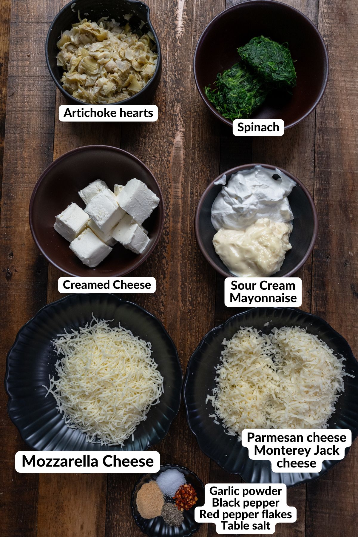 ingredients for spinach artichoke dip on table in bowls