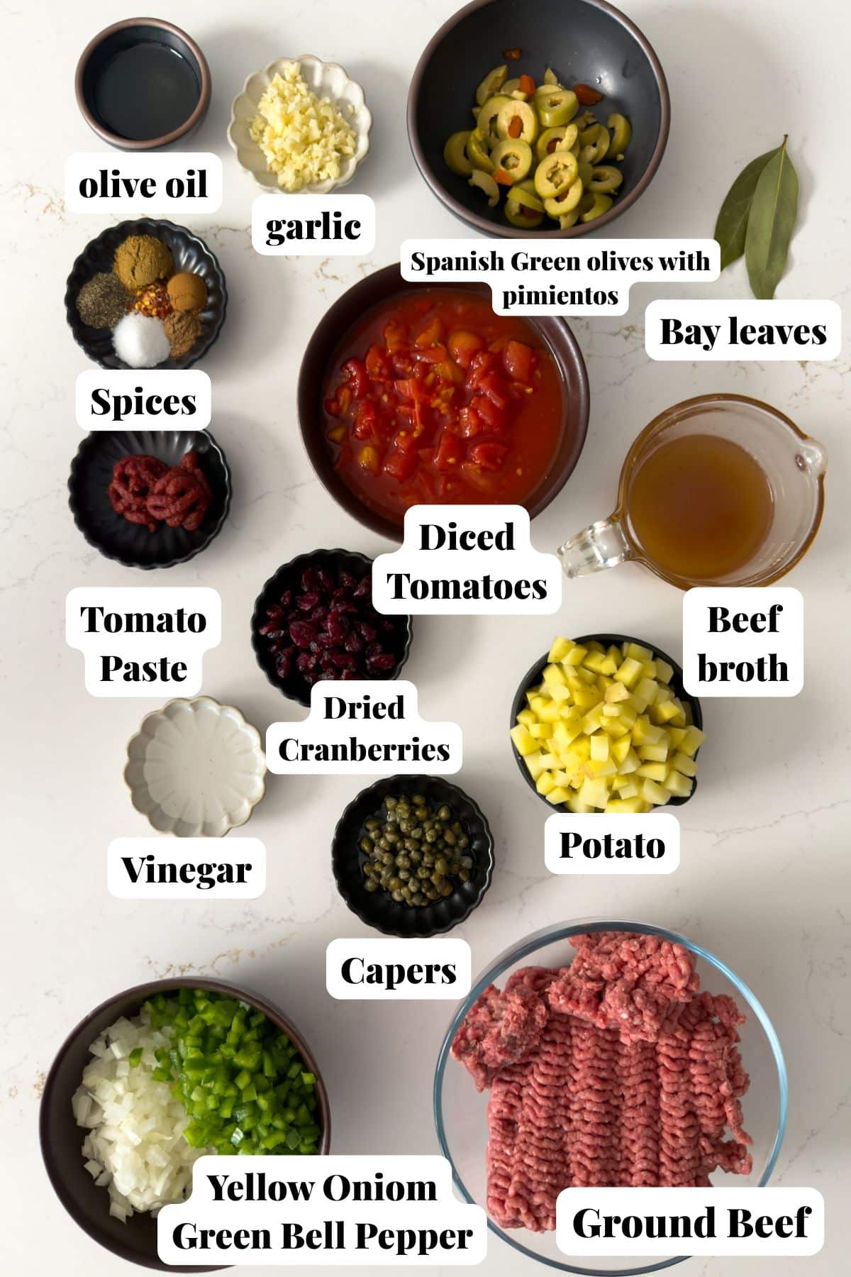 Ingredients for a picadillo on white countertop.