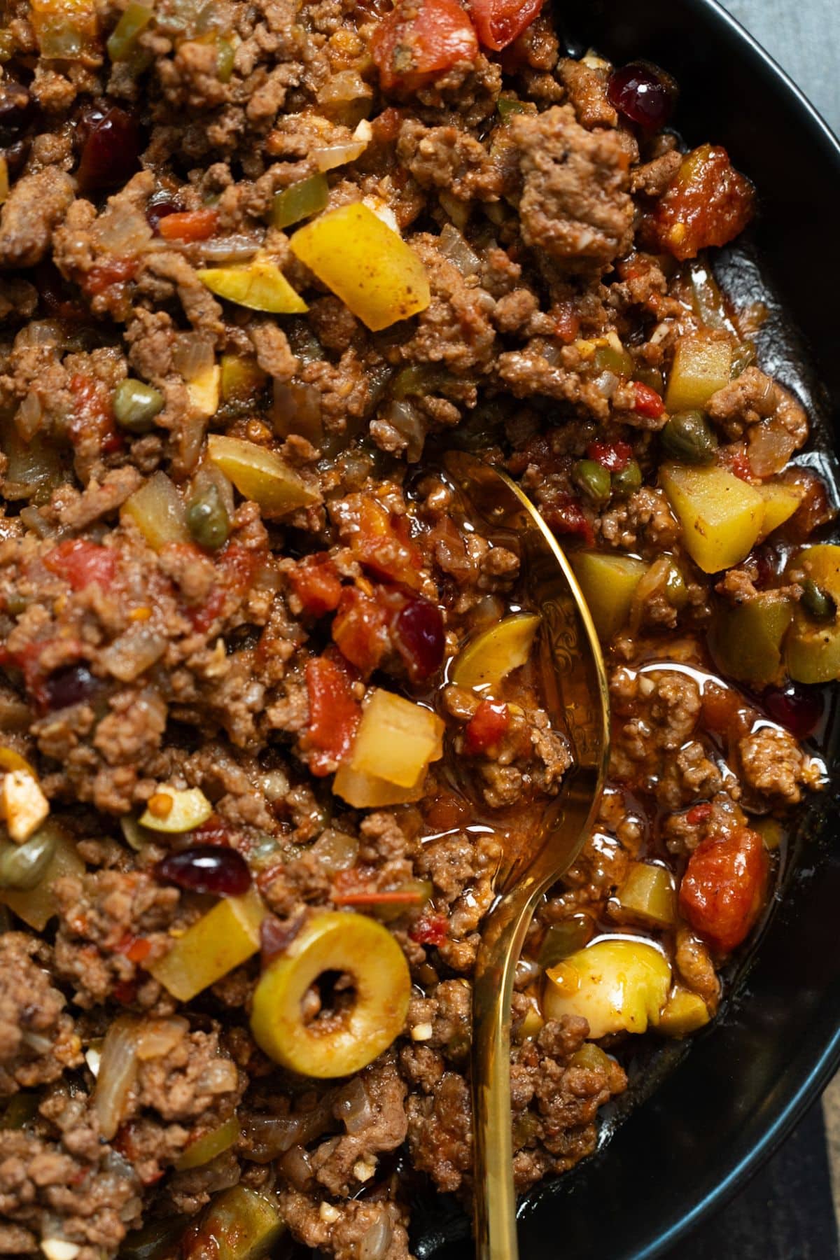A close photo of Cuban Picadillo with a spoon inside the Picadillo.